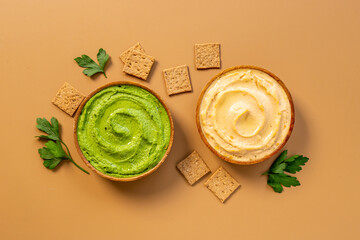 Flatlay of different types of colorful hummus in bowls. Vegan food background