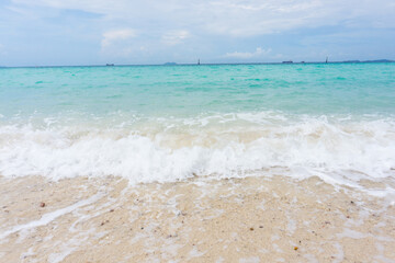 Fototapeta na wymiar Wave of the blue sea on the sand beach on vacation.