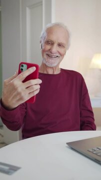 Grandpa takes funny selfies on a smartphone and looks at the resulting photos