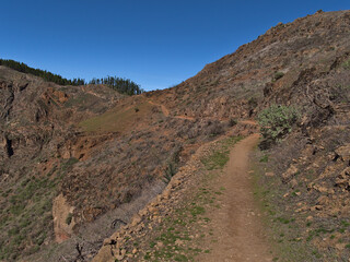 Diminishing perspective of narrow hiking trail in the mountains of island Gran Canaria, Canary Islands, Spain near Cruz de Tejeda on sunny day.