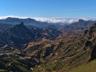 Stunning view of the colorful mountains of island Gran Canaria, Canary Islands, Spain with famous rock formation Roque Bentayga and sea of clouds.