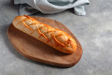 toasted sliced garlic bread baguette served on cutting board with blue linen napkin on gray stone background. bakery concept..