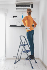 Woman cleaning aircon filters indoor unit at home.