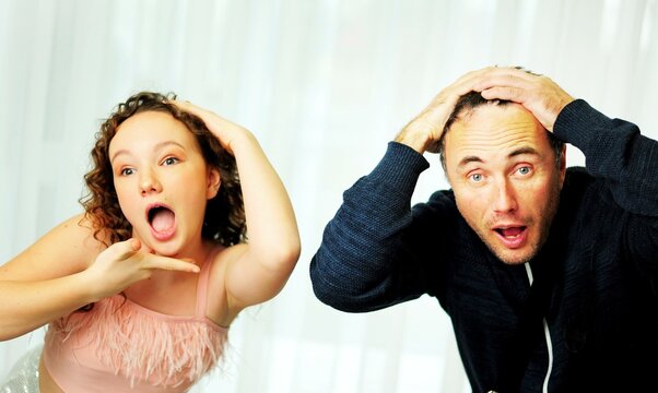 girl and father fool around standing different surprised faces have fun together a girl of 12 years and her father about 40 they are in the studio on a white background. High quality photo