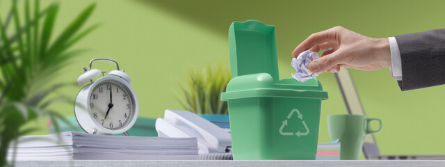 Businessman putting paper trash in a recycling bin