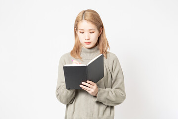 Fototapeta premium 白い背景の前に立って筆記用具を持っている若い女性