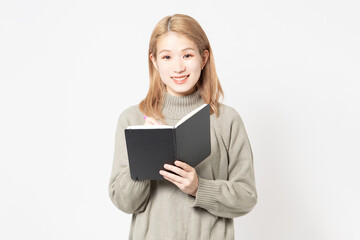 Fototapeta premium 白い背景の前に立って筆記用具を持っている若い女性