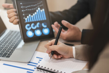 Business meeting, asian group man, woman brainstorm analyzing graph data of cost plan, discussing in board room, using touchpad or laptop computer on table or desk. People working conference room.