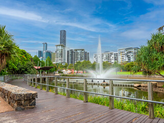 Parklands and apartment building at Roma Street in Brisbane, Australia. Fountain and lake, residential and office buildings in the background, during a bright day of summer. - obrazy, fototapety, plakaty