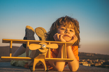 Child pilot with toy airplane dreams of traveling in summer in nature. Kids dreams. Child plays with a toy plane and dreams of becoming a pilot. Summer holidays with children.