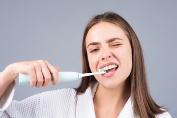 Beauty portrait of a happy beautiful woman brushing her teeth with a electric toothbrush isolated background. Dental concept.