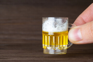 Miniature mug with beer on a wooden background