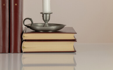 Candle holder and old style books against white background