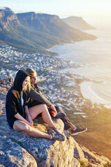Enjoying a view from above. Full length shot of a young couple sitting on a mountain top.