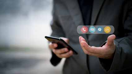 Contact us or the connected customer support hotline. Businessman using laptop and tapping contact icon on virtual screen, phone, email, address, live chat, internet, available 24 hours a day.