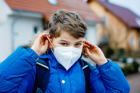 Kid boy wearing ffp medical mask on the way to school. Child backpack satchel. Schoolkid on cold autumn or winter day with warm clothes. Lockdown and quarantine time during corona pandemic disease