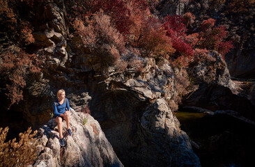 Active lifestyle. Trekking and hiking. Young woman with rucksack in the forest rock canyon.