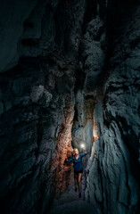 Young woman exploring a cave digged in the mountain.