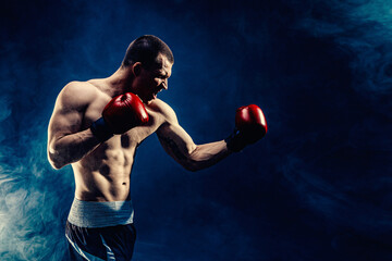 Fototapeta na wymiar Side view of sportsman muscular boxer who fighting on black smoke background. Boxing sport concept