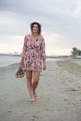 Attractive woman walking barefoot on a sandy beach. Tourist girl on the beach at summer