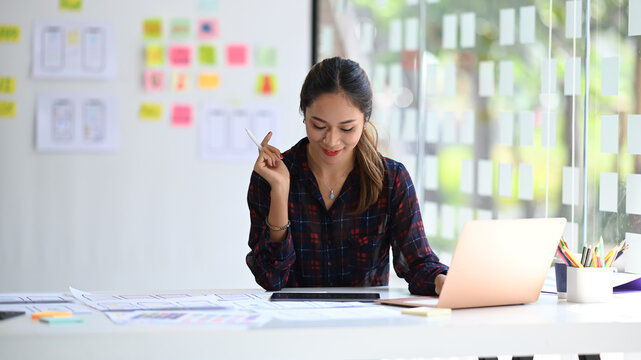 Young female UX designer working for mobile application software design at creative office. - Powered by Adobe