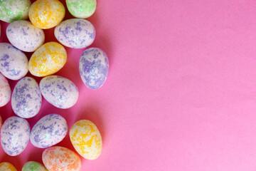 Easter eggs are multicolored on a pink background. Holiday. Eggs are small from foam plastic. Copy space. View from above. Easter. Toy.