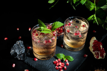 two colorful summer cocktails with pomegranate and mint on a black table