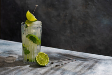 cold Mojito cocktail with rum, lime, ice cubes and mint. Tropical palm leaf shadow
