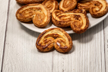 
Palmier puff pastry biscuits in white plate on a white painted wooden table