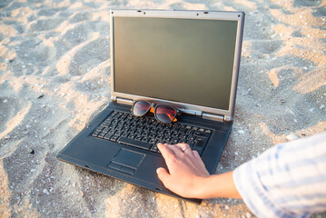 laptop on the beach in the sand. glasses against the sun. rest