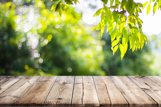 Empty wooden table with garden bokeh for a catering or food background with a country outdoor theme,Template mock up for display of product