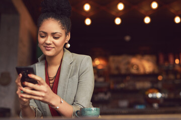Just enjoying a quick cuppa before heading to the office. Cropped shot of a young businesswoman texting on a cellphone in a cafe.