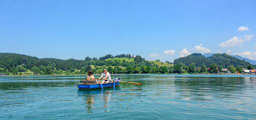 Familie mit dem Boot unterwegs auf dem idyllischen Alpsee in den Allgäuer Alpen nahe Immenstadt