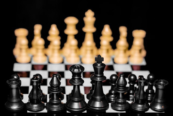 Close up of Chess pieces on a reflective mirror board surface with black background