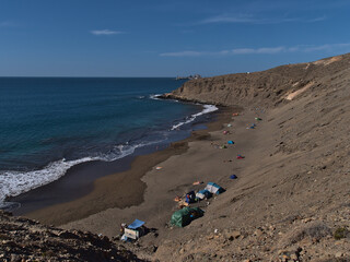 Beautiful view over remote sand beach Playa Montana Arena near Pasito Blanco on the southern coast of Gran Canaria, Canary Islands, Spain with people.