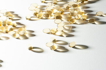 Translucent golden capsules with omega 3 lie in bulk on a light background with beautiful bokeh and beautiful translucent long shadows