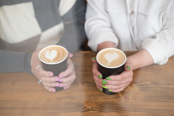cups of coffee in female hands with heart symbol