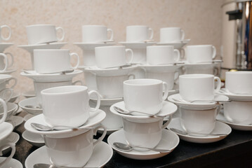Obraz na płótnie Canvas White cups for tea piled on table with plates for coffee-break