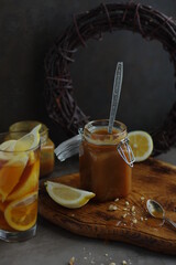 Salted caramel with lemon in a small glass jar on a wooden board. Sweet caramel sauce with citrus aroma.