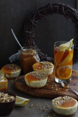 Mini cheesecakes with lemon and salted caramel on a wooden cutting board. Desserts made from cream cheese with citrus fruits.