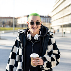 smiling lesbian woman holding disposable coffee cup, not binary and fluid gender person,...