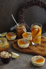 Mini cheesecakes with lemon and salted caramel on a wooden cutting board. Desserts made from cream cheese with citrus fruits.