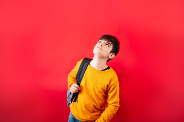 young friendly teenager with backpack on red background.