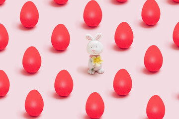 Easter pattern minimal funky concept. Little cute rabbit toy with many lovely red eggs. Pastel baby...