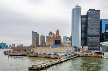 Fototapeta na wymiar Manhattan with Battery Park, wood jetty and Hudson river in the forefront, during winter evening with overcast, horizontal