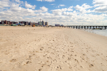 Empty Beach during sunny winter day at Coney island, Brooklyn with Pat Auletta Steeplechase Pier, Luna Park Amusement Park and Residential Buildings in the Background, New York City, horizontal