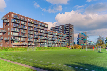 Modern brown residential apartment building near the Byparken park and football field in Ørestad....