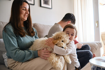 Little girl hugging her dog while enjoying time with her family at home.