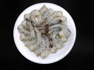 Top view raw prawns on white plate isolated on black background, Raw big tiger shrimp, copy space,  for grill or cooking, Selective focus
