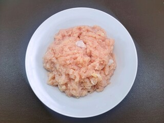 Top view of raw minced pork isolated on white background, on the   white plate, on a brown background ,fresh meat for cooking